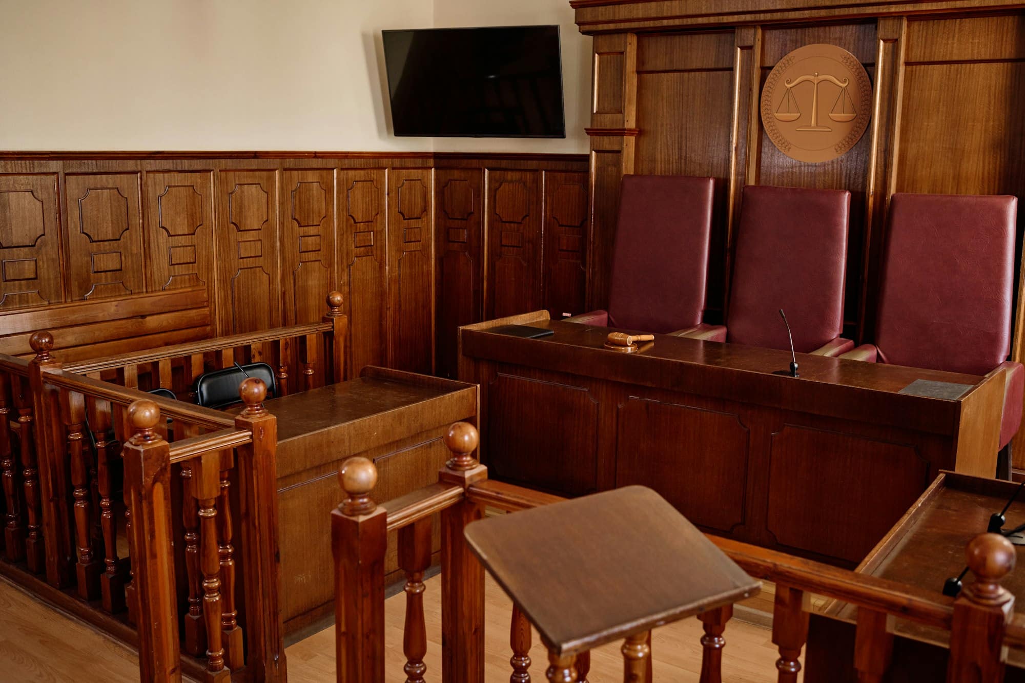 https://williamsattorneyatlaw.com/wp-content/uploads/2024/03/corner-of-courtroom-with-wooden-desks-and-railings-and-leather-chairs.jpg